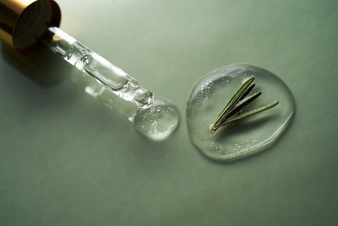 A drop of cosmetics gel with rosemary on a green background