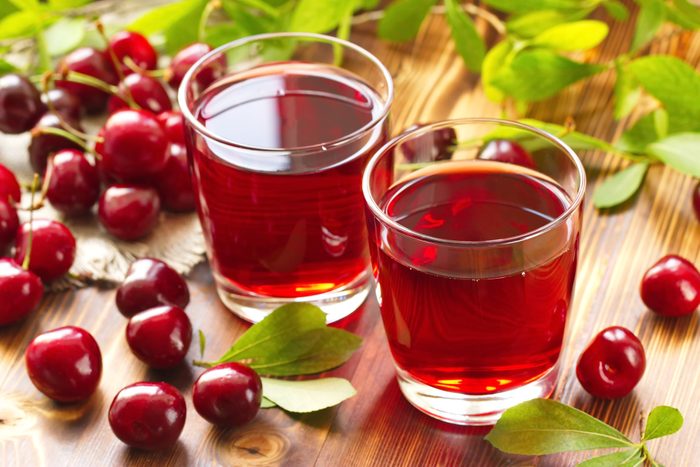 Cherry juice with fresh berries and leaves on a wooden background