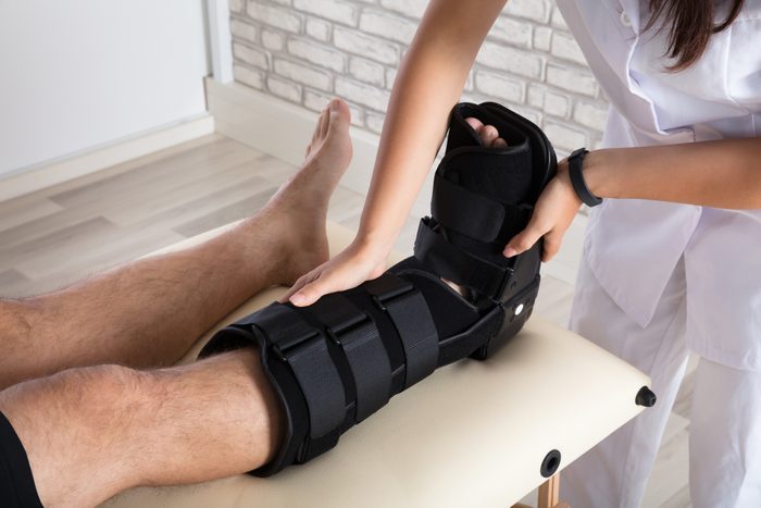 Orthopedist Putting Walking Brace To Patient's Leg