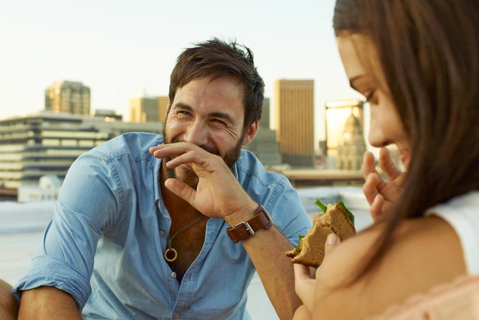 couple laughing together while eating lunch outside on a rooftop