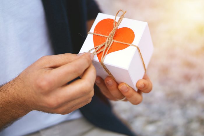 hands opening a gift with a heart on the box