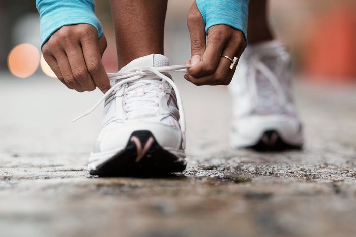 close up of hands of a Runner Tying Shoelaces on white sneakers outdoors