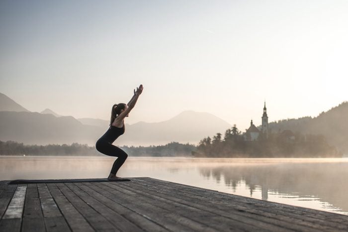 Woman in Yoga Chair Position on Pier Overlooking Lake Bled