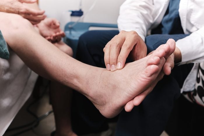 medical doctor taking patient's pulse in the foot
