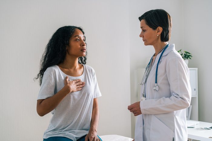 Worried mature female doctor carefully listening to complaints of African-American patient