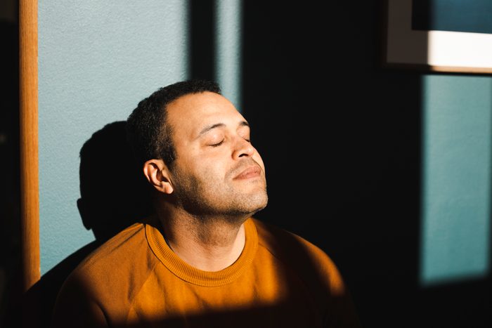 Man with eyes closed enjoying sunlight at home
