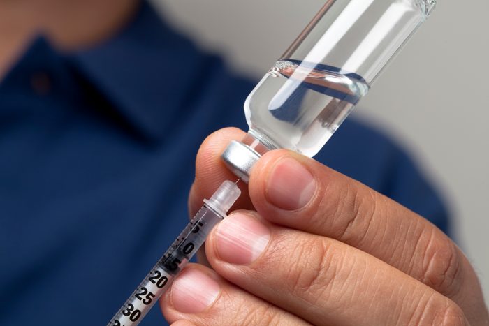 Man fills syringe with right dosage for an insulin shot