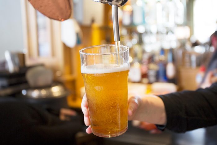 close up of a hand filling a glass of beer at a bar