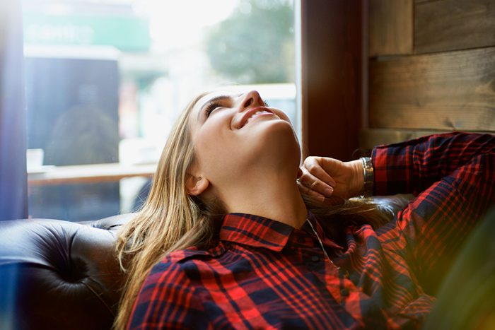 Woman looking happy relaxing on sofa and daydreaming