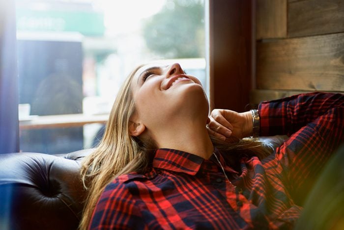 Woman looking happy relaxing on sofa and daydreaming