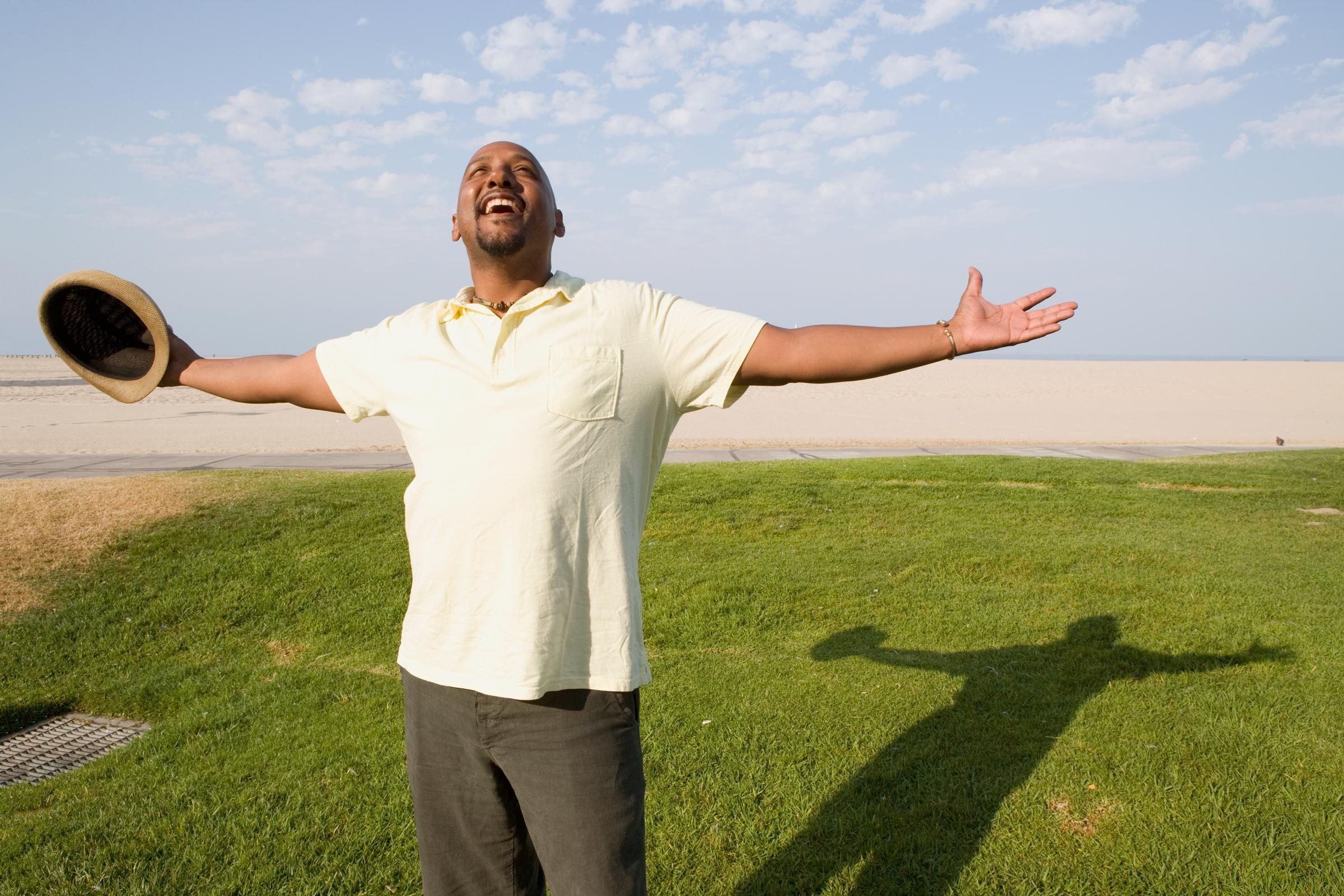 Happy man outside holding his arms out and looking up at the sky|