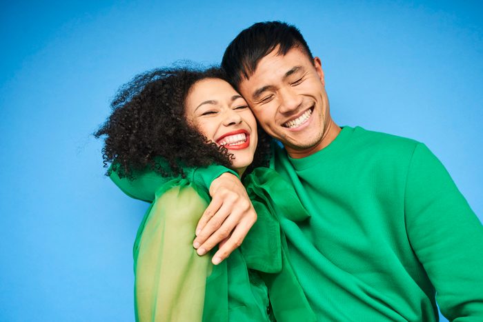 смеющиеся мужчина и женщина, одетые в зеленое на синем фоне