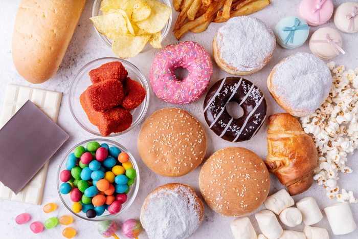 Unhealthy food and fast food with donuts, chocolate, burgers and sweets top view