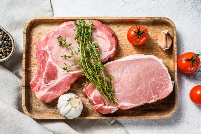Raw pork cutlet. Organic meat steak. White background. Top view
