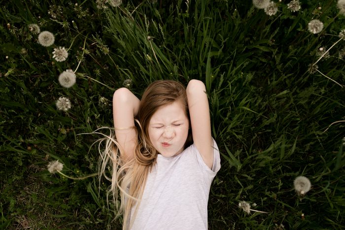 Cute girl lying amidst dandelions in field