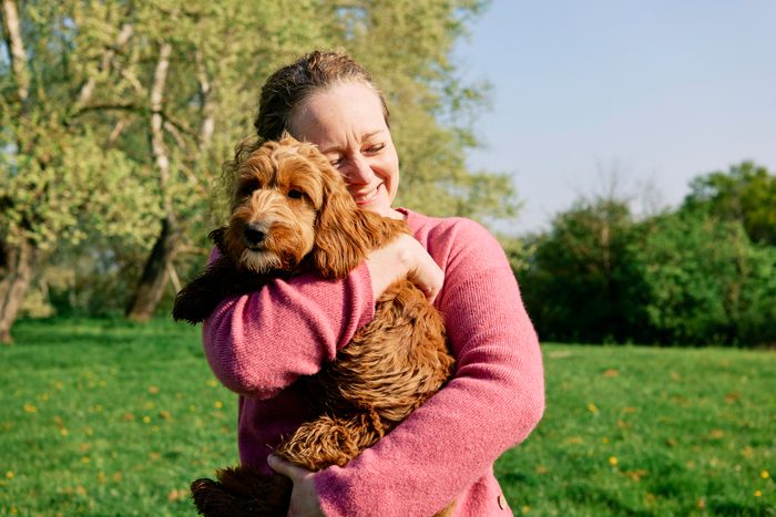 Woman cuddling her dog in a field