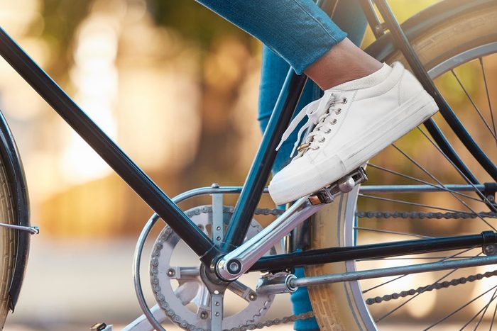 Bike, shoes and cycling with a woman cyclist riding her bicycle outside on the road or street during the day. Sport, exercise and fitness with a female rider on transport with wheels and pedals
