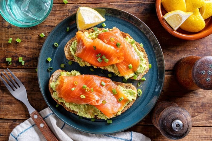 Avocado and Smoked Salmon Toast on a blue plate on a wood table