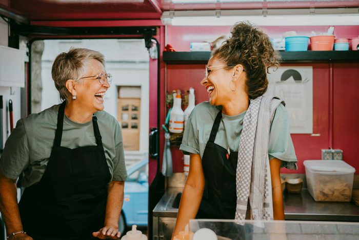 Две женщины смеются вместе на работе в фургоне с едой