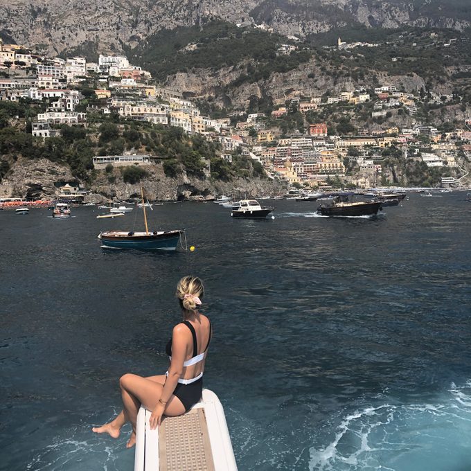 Anna Kloots sitting on the edge of a dock over looking the water and capri