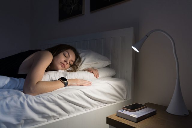 Young Woman Sleeping with smart watch at night With Smart Watch Tracker At Night