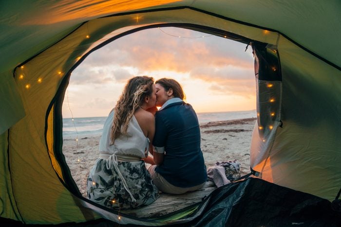Young adult couple admiring the sunset in a tent on the beach