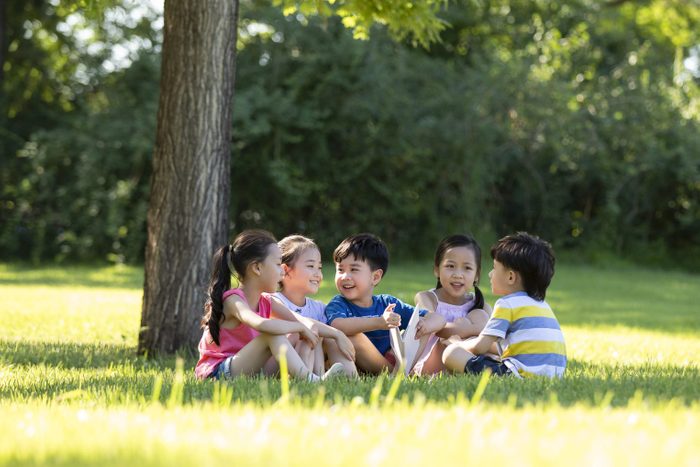 happy group of children sitting under a tree for a shade break