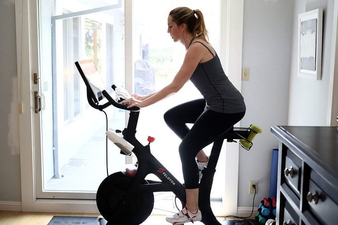 Woman rides her Peloton exercise bike at her home