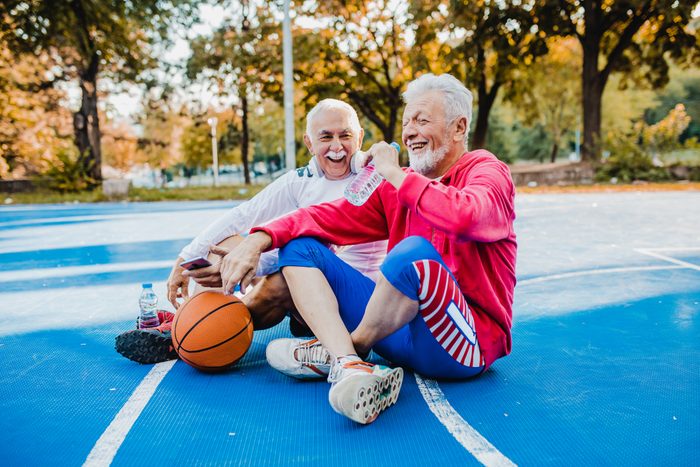 Two active senior men on basketball field taking a break from sport activity