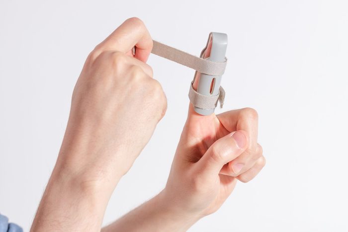 a man joining Velcro on a plastic splint for his fractured finger by dog walking