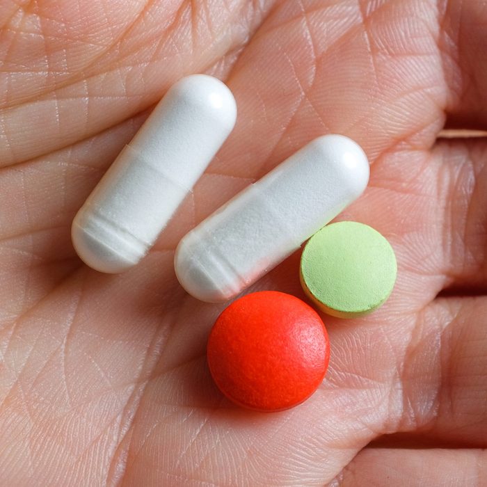 White and colored capsules and tablets in the hand of a girl or woman. Taking vitamins, painkillers, medications, food additives. The concept of prevention and treatment of diseases, health care and medicine. Pregnancy planning, filling in deficits.