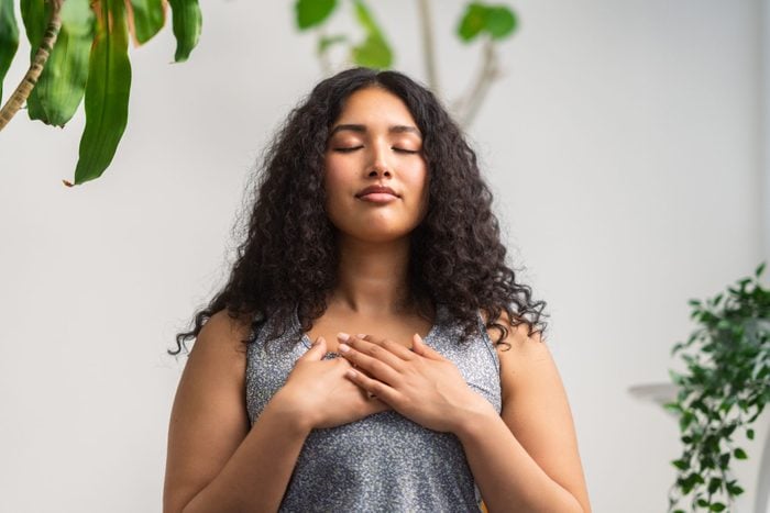Beautiful multiracial woman doing breathing exercise at home