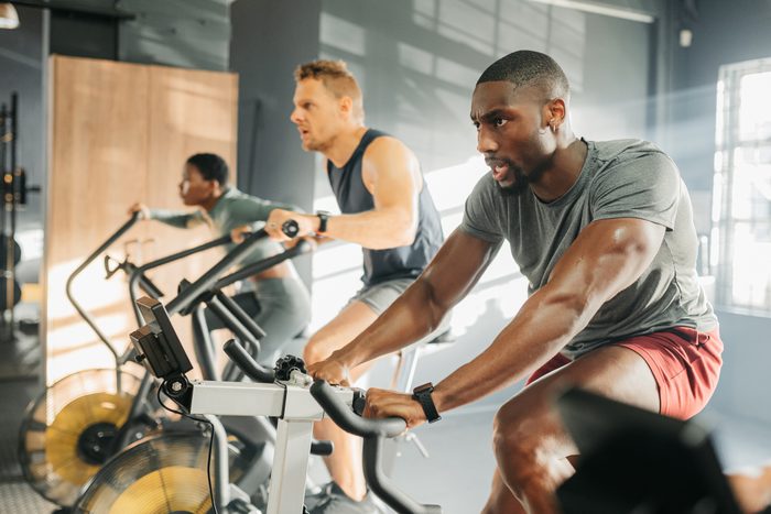 Workout gym and cycling exercise class for endurance fitness with black people and caucasian man. Cycle athlete men and woman training lesson group with focus, concentration and dedication.