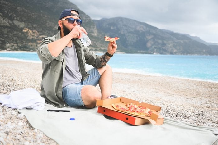 man resting on the beach and eat pizza