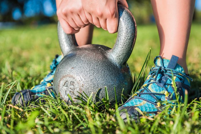 Woman's legs with sneakers in grass with 45 pound kettlebell