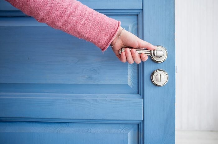 hand on the doorknob of a blue door