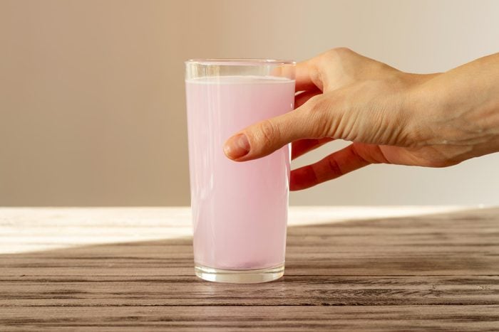 hand holding a pink electrolyte drink to increase hydration during the summer time