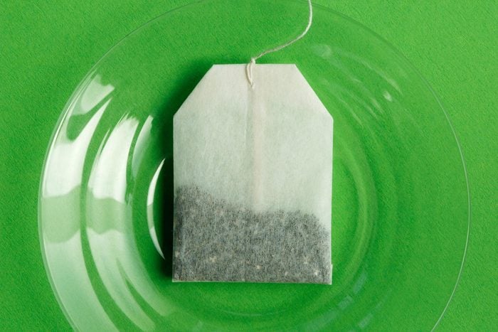 Mint Tea bag on a clear plate with a green background