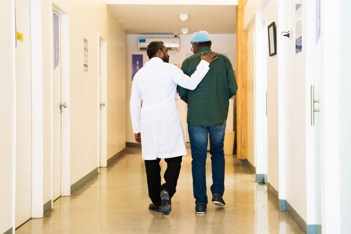 Rear view of doctor with patient in corridor