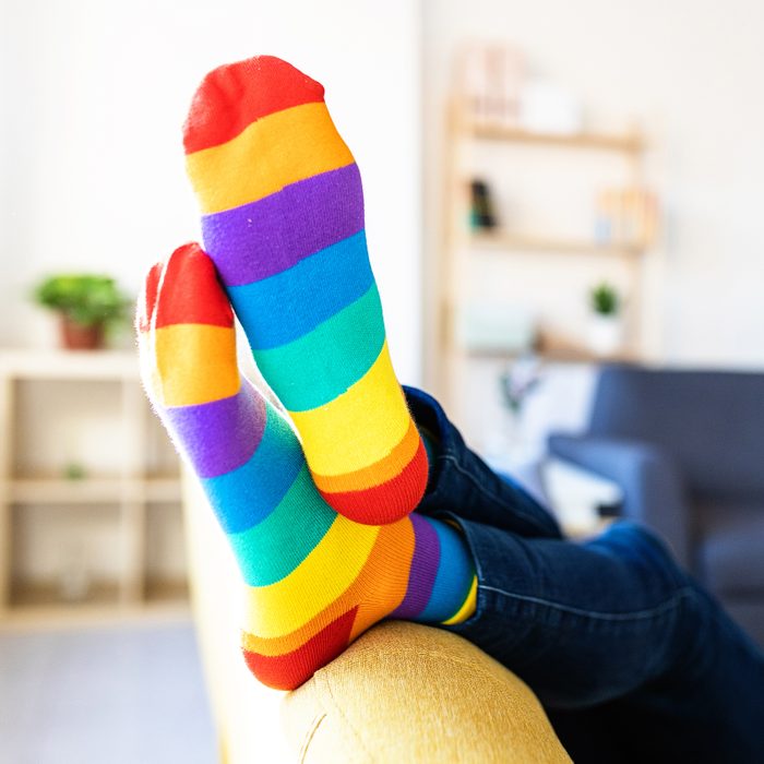 person on a couch wearing rainbow pride month socks
