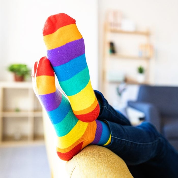 person on a couch wearing rainbow pride month socks