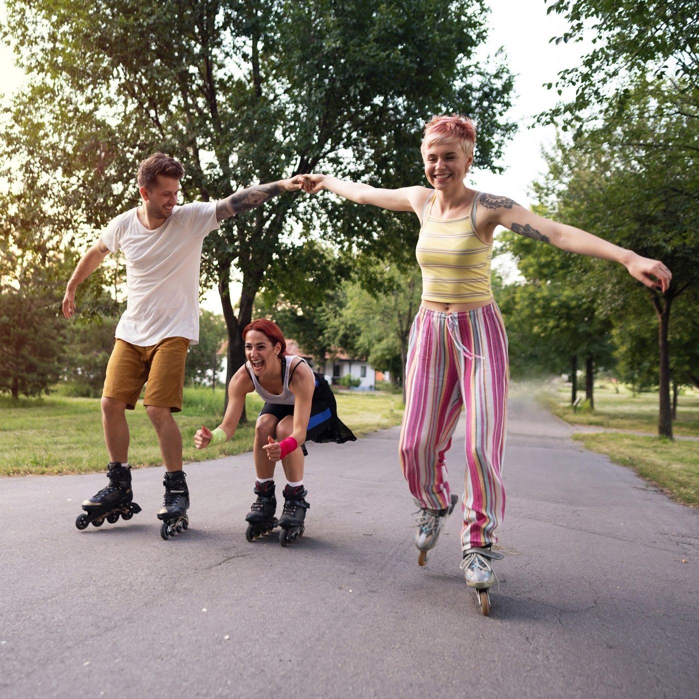 Smiling friends having fun roller skating in the park