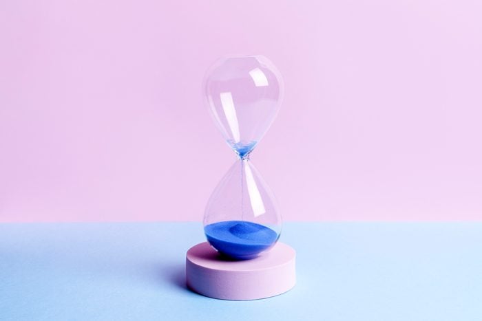 Blue Colored Sand Hourglass On Blue And Pink Background