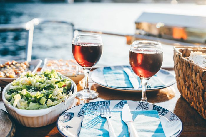 Outdoor dinner setting with red wine on the yacht at sunset.