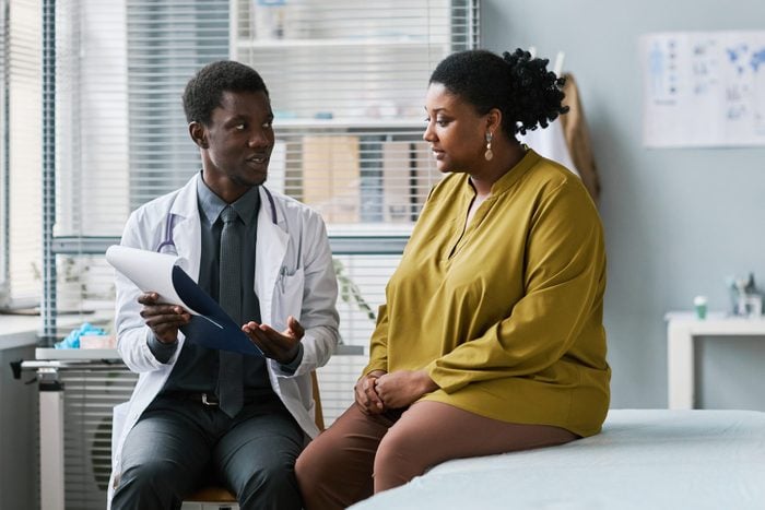 Overweight black woman talking to doctor in medical clinic