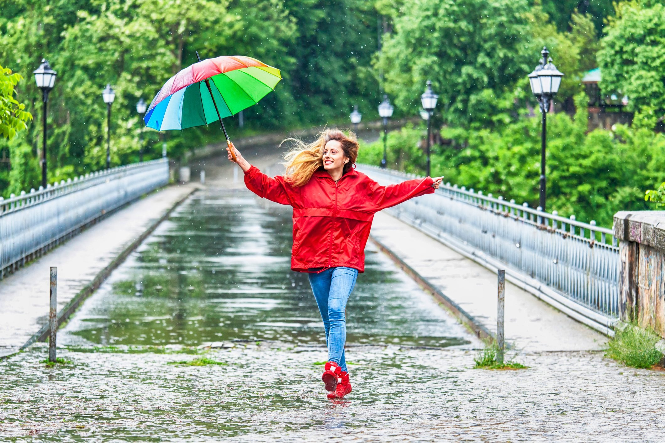 Beautiful girl with umbrella dancing in the rain|