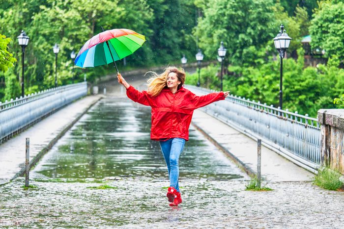 Beautiful girl with umbrella dancing in the rain