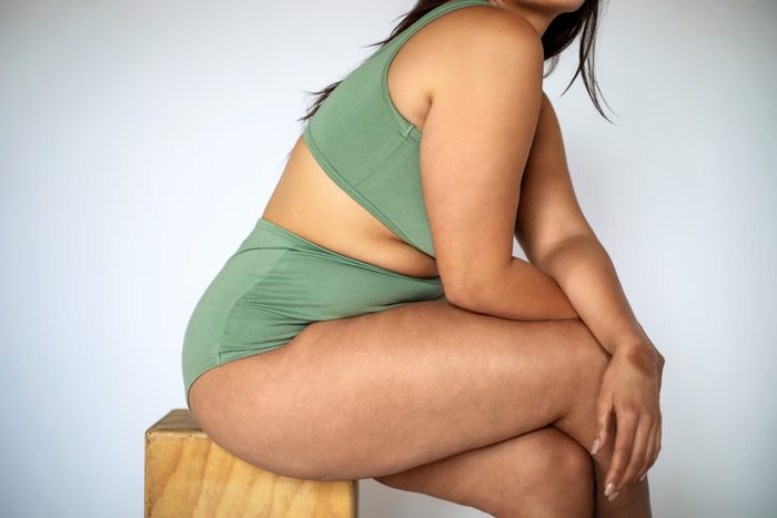 Plus size woman in lingerie sitting on a stool