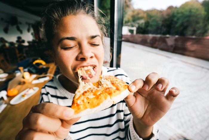 woman eating a cheesy pizza