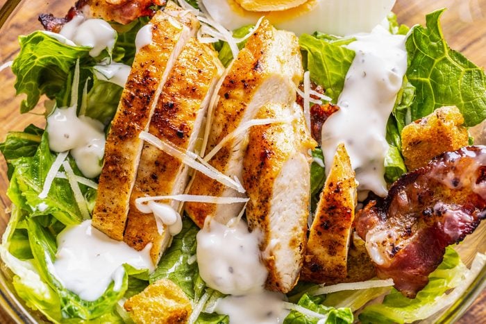 Closeup shot of Caesar Salad with Grilled Chicken, Garlic Dressing, Baked Bacon and Croutons